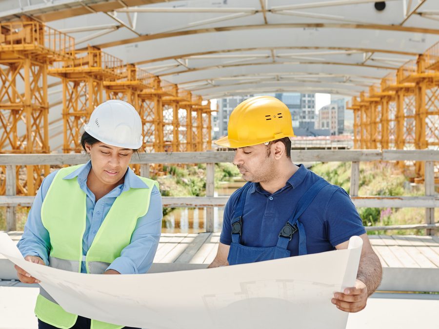 Construction managers reviewing blueprints on site